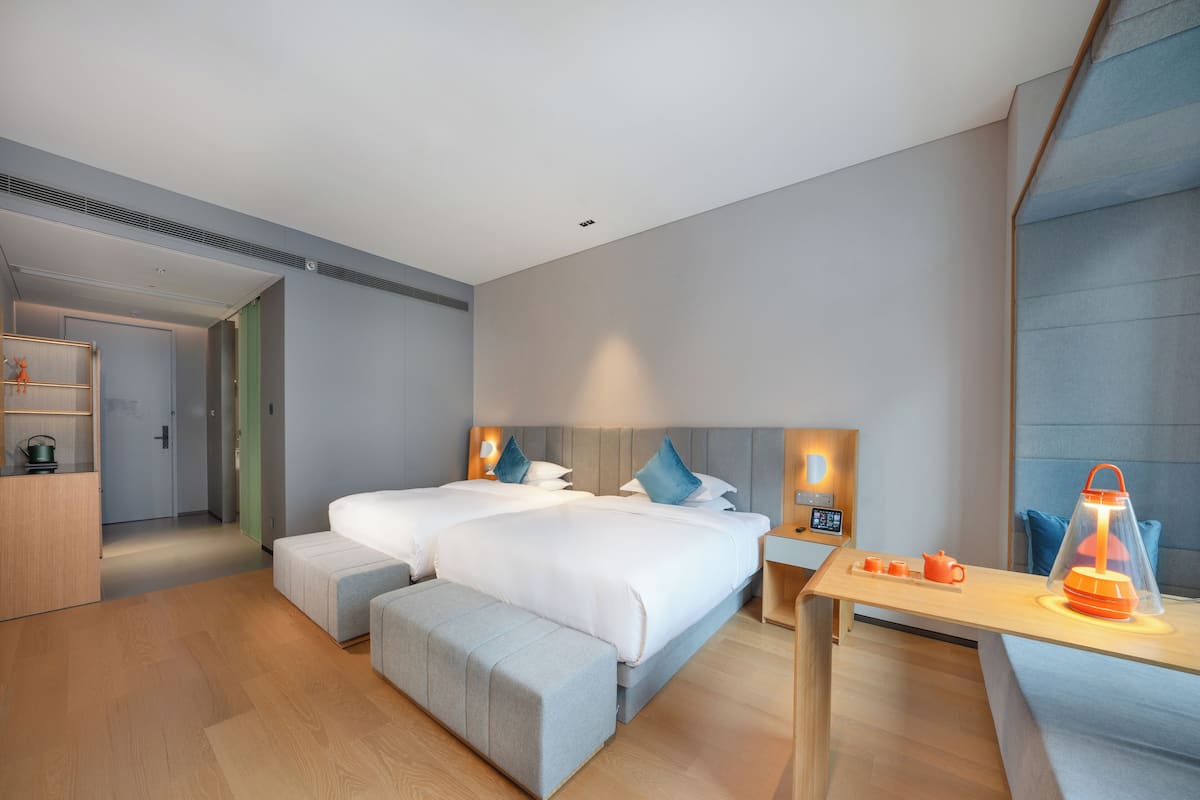 Una habitación de hotel moderna con dos camas, un escritorio y zona de estar.