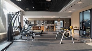 Un gimnasio moderno con diversos equipos de ejercicio, una zona de recepción y una máquina expendedora.