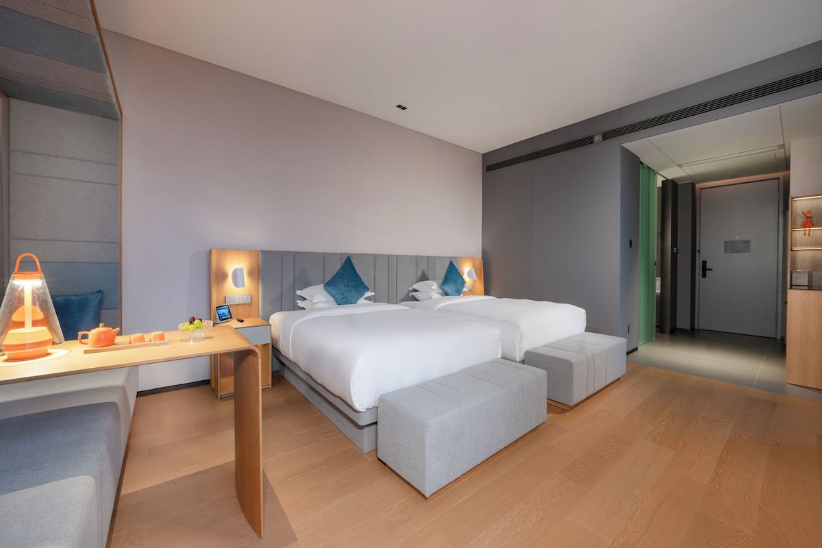 Una habitación de hotel moderna con una cama grande, mesitas de noche, un escritorio y una silla.