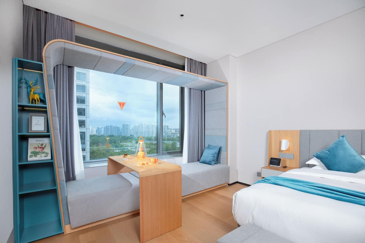 Una habitación de hotel moderna con una cama, un escritorio y una zona de estar junto a la ventana.
