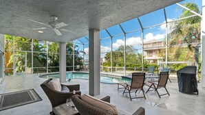 Ein überdachter Außenbereich mit Pool, Korbmöbeln und Deckenventilator.