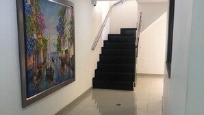En hall med en stor målning som föreställer en kanalvy, en trappa och en taklampa.
