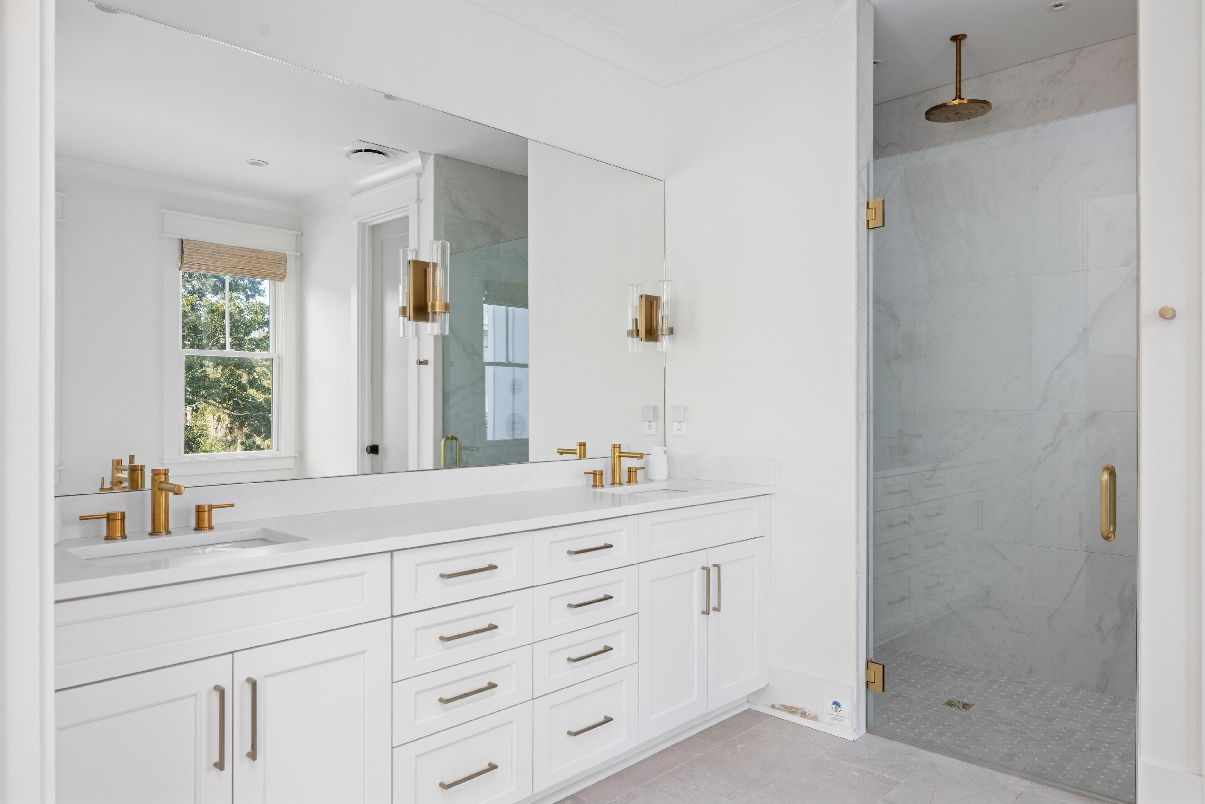 Un baño moderno con un espejo grande, dos lavamanos y una ducha a ras de suelo.