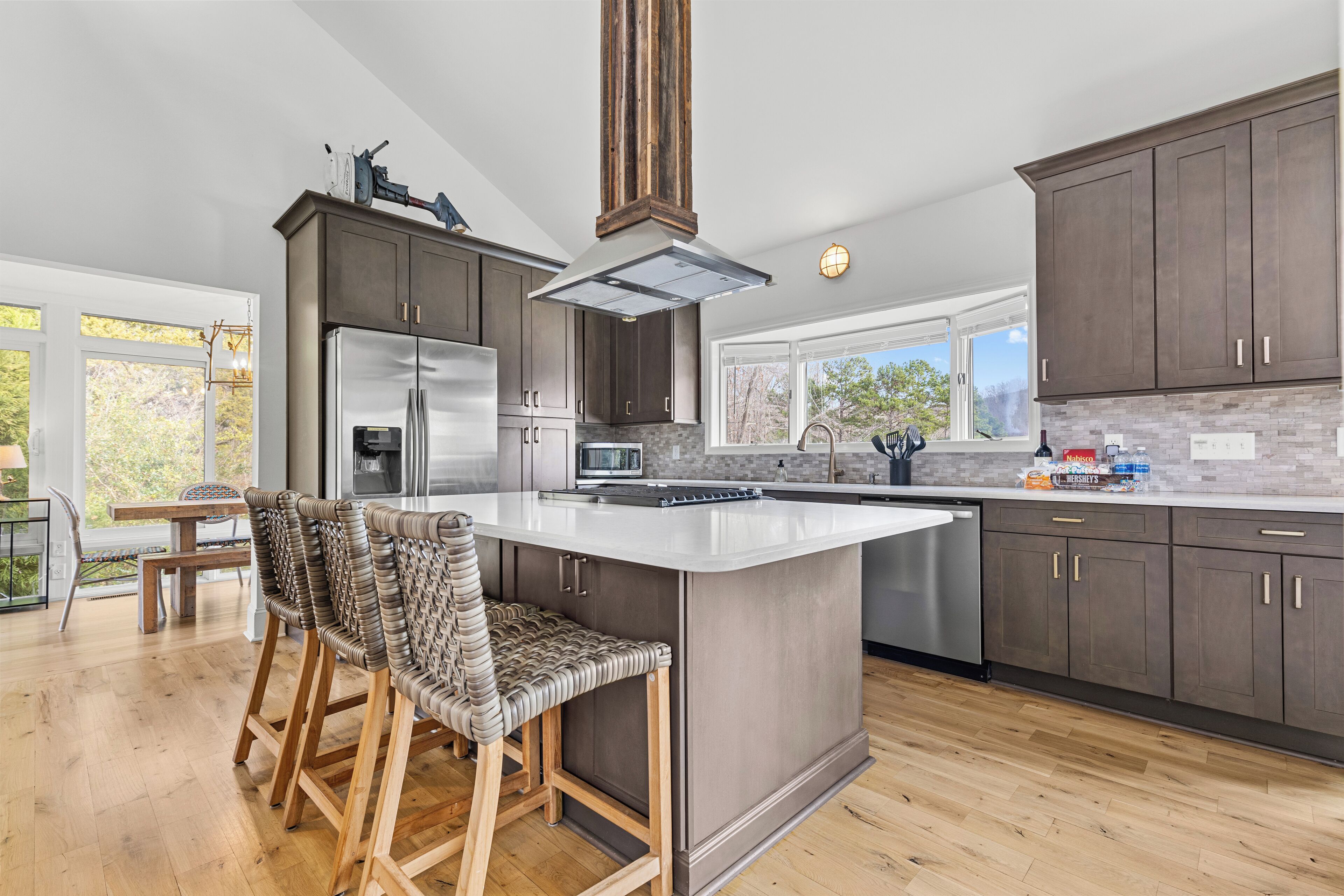 A modern kitchen with dark wood cabinets, a stainless steel refrigerator, and a large island with bar stools.