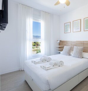 A hotel room with a bed, white curtains, a ceiling fan, and framed artwork on the wall. - Ref. 506615 (Motril)