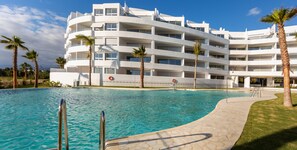 Enjoy a refreshing swim in the pool surrounded by lush greenery and palm trees.