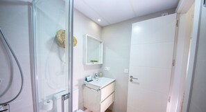 Bathroom features a glass-enclosed shower, sink, and mirror.