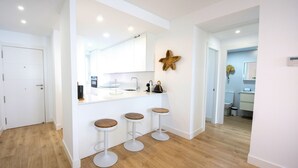 A modern kitchen with white cabinets, a central island with stools, and a starfish decoration on the wall. - Ref. 502550 (Motril)