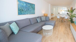 A modern living room with a grey sectional sofa, a round white coffee table, a ceiling fan, and a dining area with a table and chairs. - Ref. 502550 (Motril)