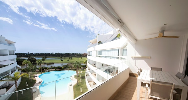 Enjoy a room with a balcony overlooking the pool and golf course, featuring a dining table and chairs.