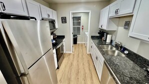 A modern kitchen with stainless steel appliances, granite countertops, and white cabinetry.