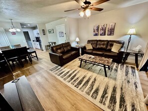 A living room with a brown leather sofa, a coffee table, and a patterned rug.