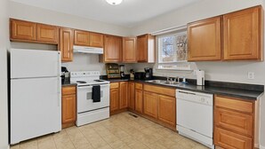A kitchen with wooden cabinets, a white refrigerator, stove, and dishwasher. - All New Sleeps 6/Old Town Arvada (Arvada)
