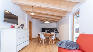 Een knus woongedeelte met een eethoek, een kitchenette en een rode bank.