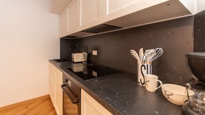 Een keuken met witte kastjes, een zwart aanrecht en een koffiezetapparaat.