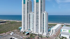Un hôtel de grande hauteur doté de nombreux balcons, d’un espace piscine et offrant une vue sur la plage.