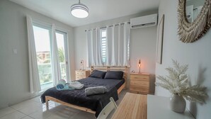 A modern bedroom with a bed, bedside tables, a desk, and a chair. - Spacious and Modern Beach House With Pool (Hatillo)