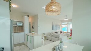 A modern kitchen with a dining area, a sofa, and a hanging light fixture. - Spacious and Modern Beach House With Pool (Hatillo)