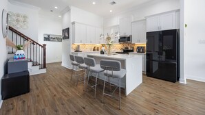 A modern kitchen with white cabinetry, a black refrigerator, and a central island with bar stools.