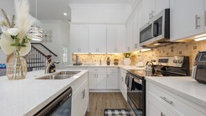 A modern kitchen with white cabinets, a dishwasher, a microwave, and a stove.