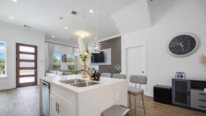 A modern kitchen with a central island, a built-in dishwasher, and a large window.