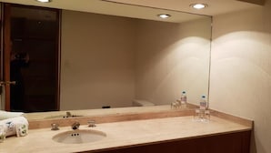 Un baño de hotel con lavabo, espejo y dos botellas de agua.