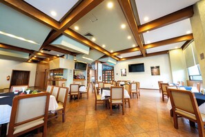 Un restaurant avec des poutres en bois, des carreaux au sol et un espace bar.