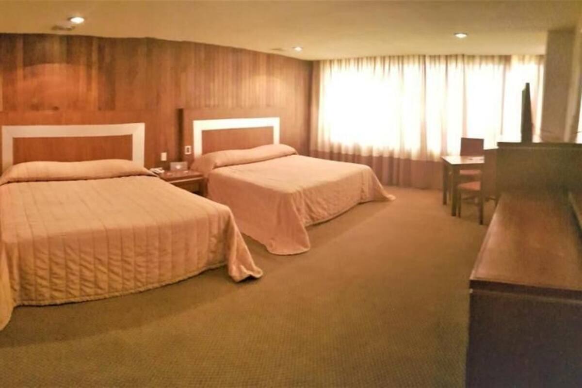 Une chambre d’hôtel avec deux lits, un bureau et une télévision.