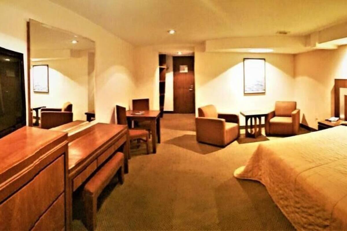 Une chambre d’hôtel avec un grand lit, un bureau avec une chaise, une télévision et une petite table.