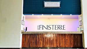 Un mostrador de recepción con un cartel que dice "RECEPTION FRONT DESK" y "HOTEL FINISTERE".