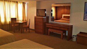 Una habitación de hotel con cama, escritorio, silla, televisión y un cuadro en la pared.
