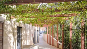 A covered walkway with a concrete floor, bordered by a low wall and a metal fence on one side. - Pigonnet by Interhome (Aix en Provence)