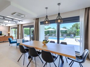 Un comedor moderno con una mesa larga, sillas negras e iluminación colgante.