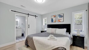 Ein modernes Schlafzimmer mit Bett, Nachttischen, einem Kleiderschrank und Kunstwerken an der Wand.