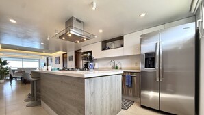 A modern kitchen with a central island, stainless steel appliances, and a dining area with bar stools.
