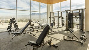 A gym with various exercise equipment, large windows, and a city view.