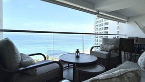 A balcony with a view of the ocean, wicker furniture, and a table with a lantern.
