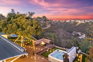Terraza en la azotea con jacuzzi, mobiliario exterior e iluminación con guirnaldas.