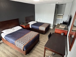 A hotel room with two beds, a desk, and a chair.