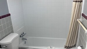 Een badkamer met een bad, toilet, wastafel en douchegordijn.
