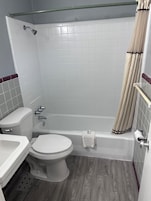 A bathroom with a bathtub, toilet, sink, and shower curtain.