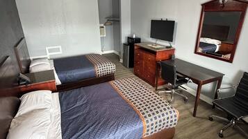 A hotel room with two beds, a desk, a chair, a TV, and a mirror.