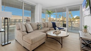 A modern living room with a beige sectional sofa, a round coffee table, and a view of the city through large windows.