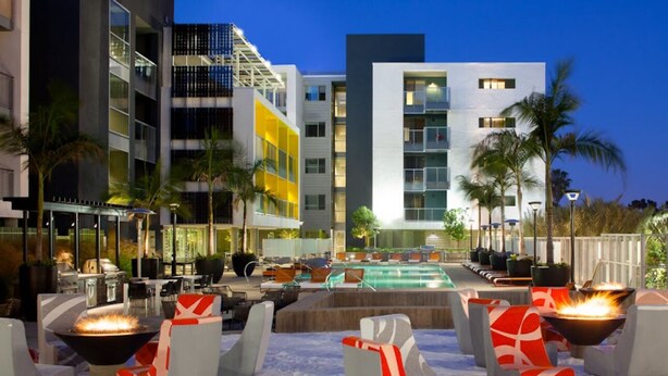 A modern hotel with a pool area, outdoor seating, and a fire pit.