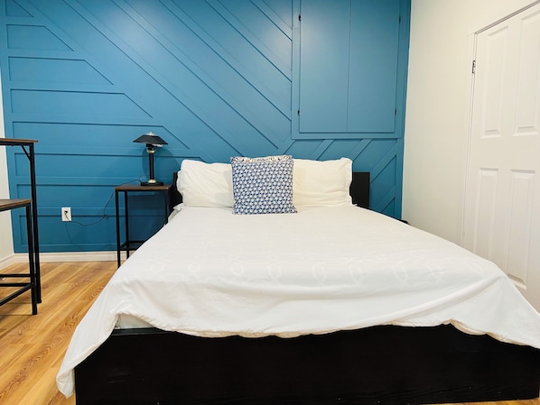 A bedroom with a bed, a nightstand, a lamp, and a wardrobe.