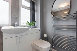 Un baño moderno con un lavamanos blanco, un inodoro y un perchero para toallas.