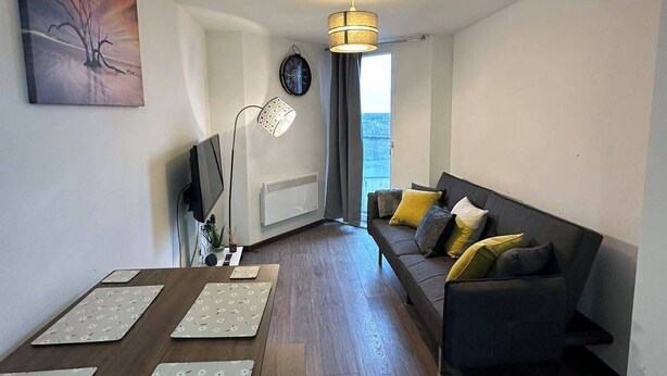 A modern living room with a dark sofa, a coffee table, a floor lamp, and a painting on the wall. - 1BR-Sleeps4-Parking-ClosetoCentre (Birmingham)