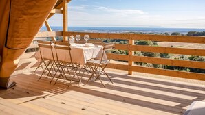 Eine Holzterrasse mit einem Tisch für zwei Personen, mit Blick auf eine reizvolle Landschaft.