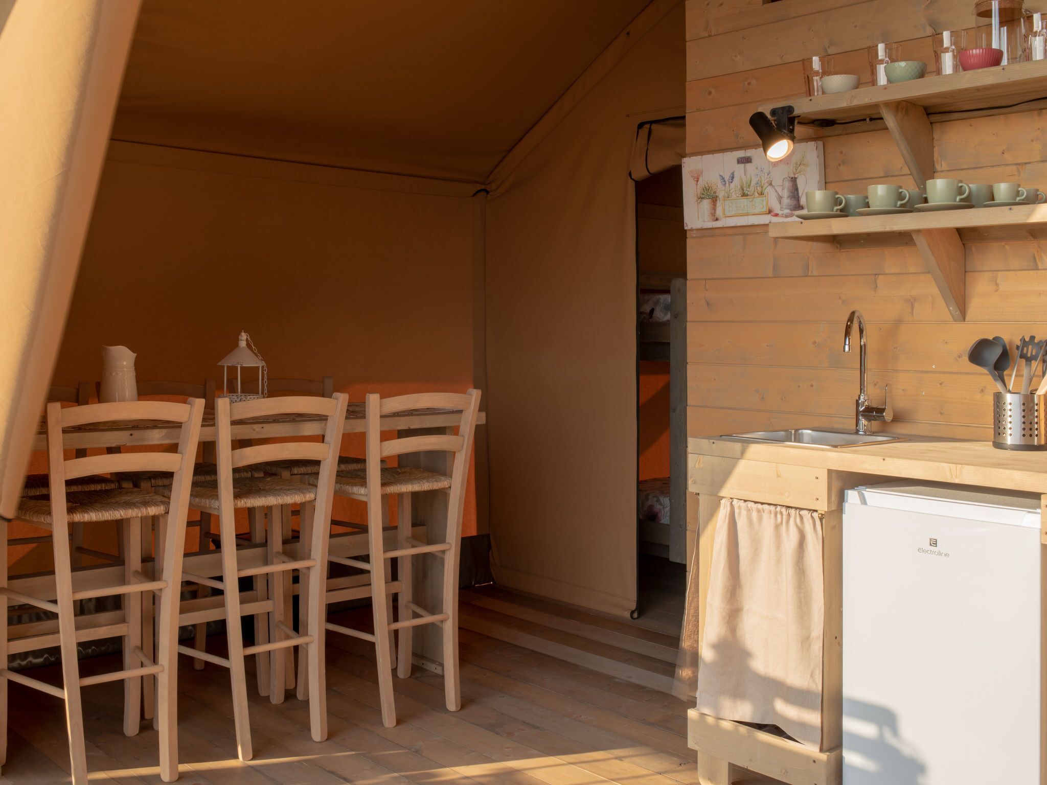 A compact kitchen with wooden chairs and a small white refrigerator.