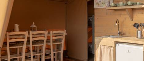 A compact kitchen with wooden chairs and a small white refrigerator.